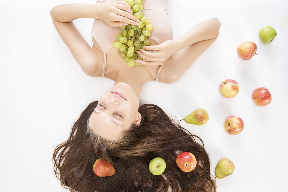 A woman lying on the ground with fruit around her symbolising the peace and calm therapy and counselling can bring