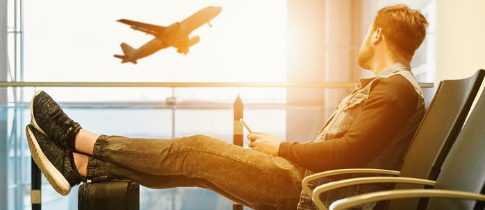 A man sitting at an airport lounge looking an aeroplane