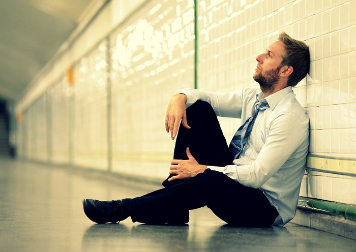 A man sitting down on a floor looking very upset with relationship problems